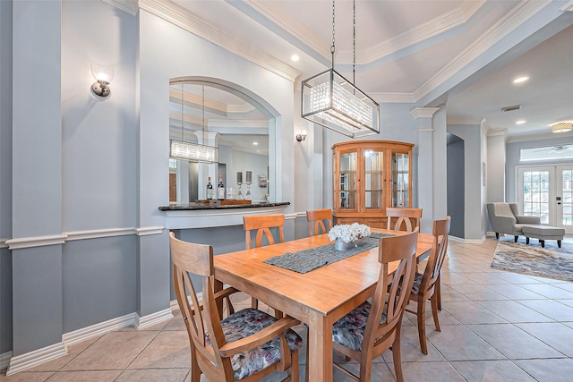 dining area with french doors, a raised ceiling, ornate columns, and light tile patterned flooring