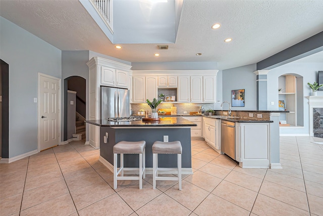 kitchen featuring arched walkways, stainless steel appliances, and light tile patterned flooring