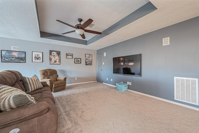 living area featuring a textured ceiling, visible vents, a tray ceiling, and carpet flooring