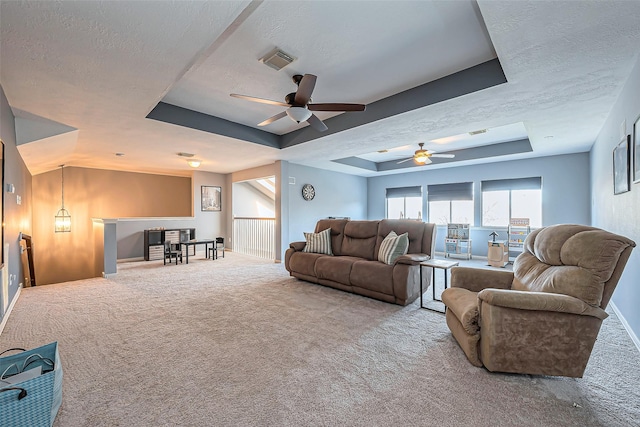 carpeted living room featuring visible vents, a raised ceiling, and a textured ceiling