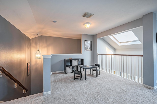 interior space featuring vaulted ceiling with skylight, visible vents, carpet flooring, and an upstairs landing