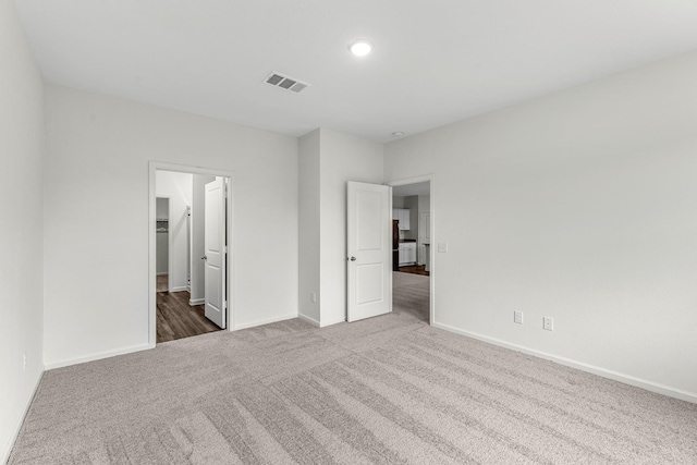 unfurnished bedroom with carpet floors, baseboards, a spacious closet, and visible vents