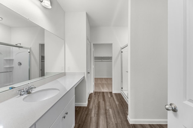 bathroom featuring a walk in closet, a shower stall, and wood finished floors