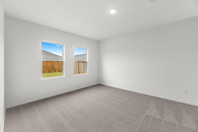 carpeted spare room with visible vents and baseboards