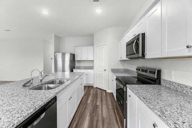 kitchen featuring stainless steel appliances, a sink, white cabinets, light stone countertops, and dark wood finished floors