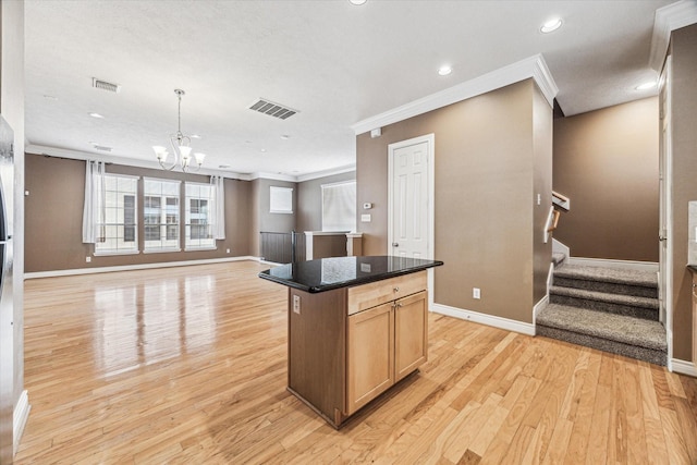 kitchen with crown molding, light wood-type flooring, a kitchen island, and baseboards