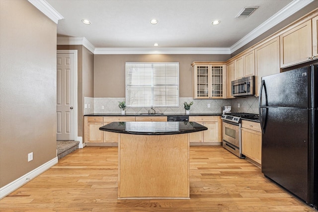 kitchen with appliances with stainless steel finishes, light brown cabinets, and visible vents