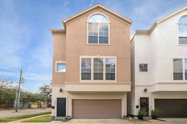 view of property featuring driveway, an attached garage, and stucco siding