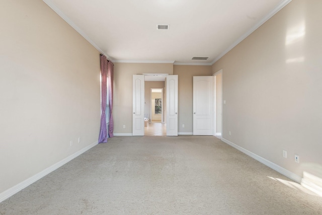 empty room featuring light carpet, ornamental molding, visible vents, and baseboards