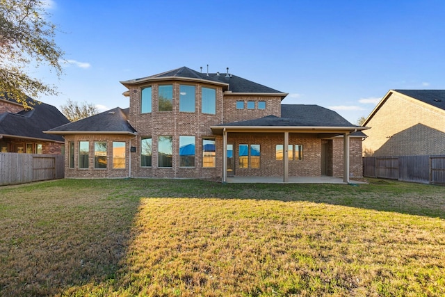 back of house with a patio area, a fenced backyard, a lawn, and brick siding