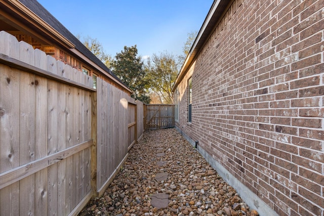 view of side of home with brick siding and fence