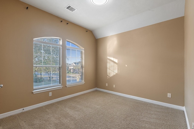 spare room with lofted ceiling, carpet flooring, visible vents, and baseboards