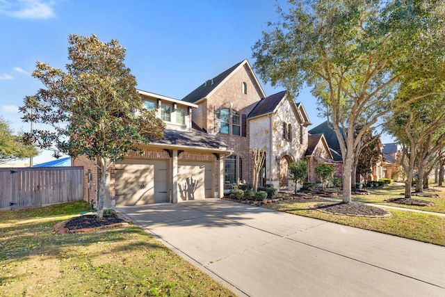 traditional-style home with a garage, brick siding, fence, concrete driveway, and a front lawn