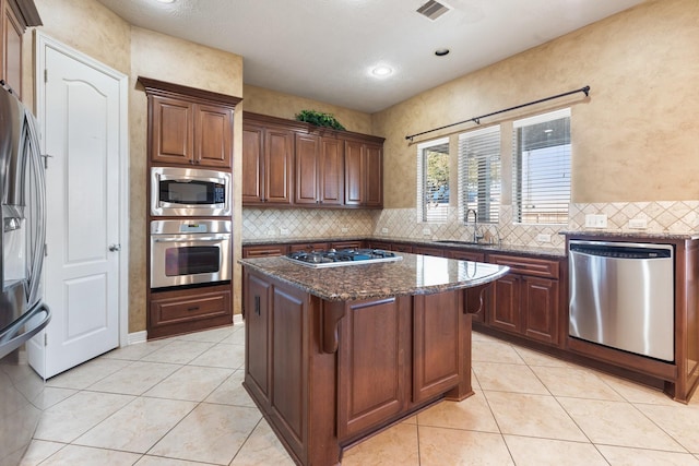 kitchen with light tile patterned flooring, stainless steel appliances, a sink, visible vents, and decorative backsplash