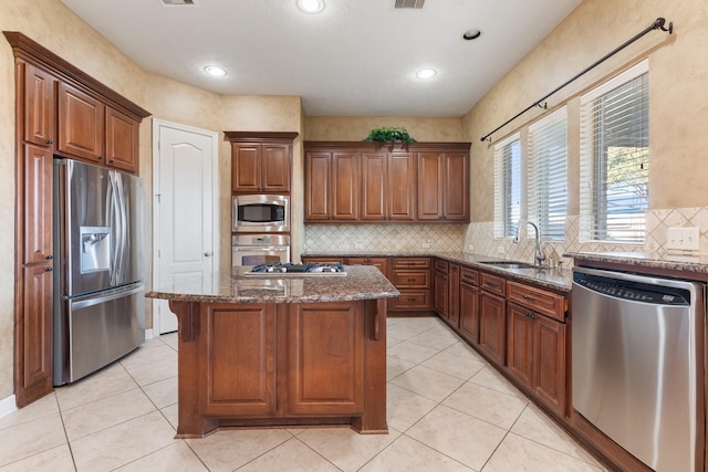 kitchen with stainless steel appliances, a kitchen island, a sink, tasteful backsplash, and dark stone countertops