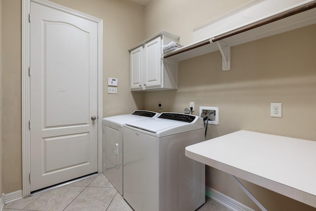 clothes washing area with cabinet space, independent washer and dryer, baseboards, and light tile patterned floors