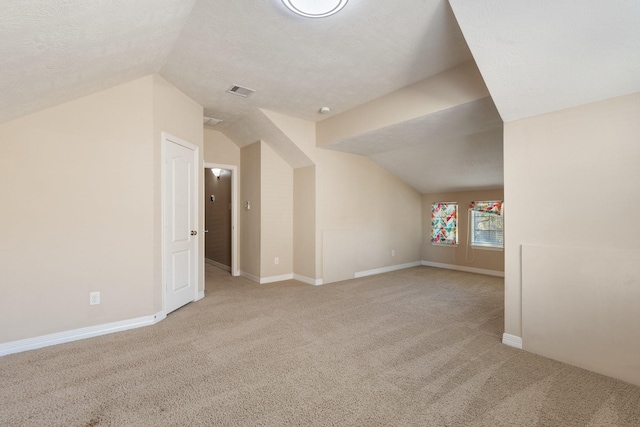 bonus room with lofted ceiling, a textured ceiling, light carpet, visible vents, and baseboards