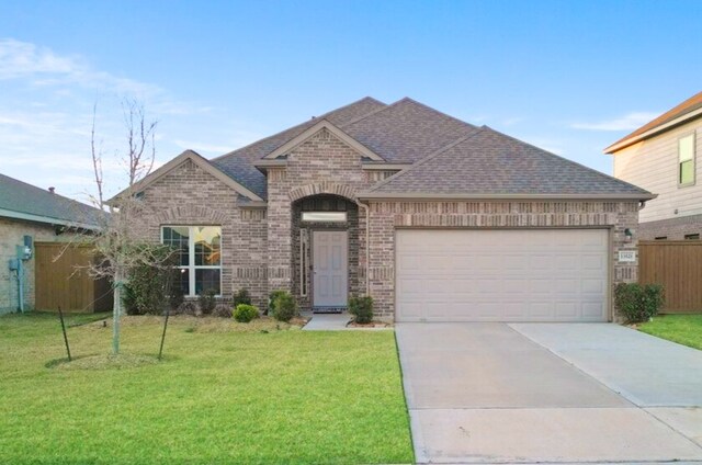 view of front of property featuring brick siding, concrete driveway, a front yard, roof with shingles, and an attached garage