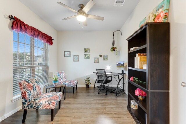 office area featuring light wood finished floors, visible vents, baseboards, and ceiling fan