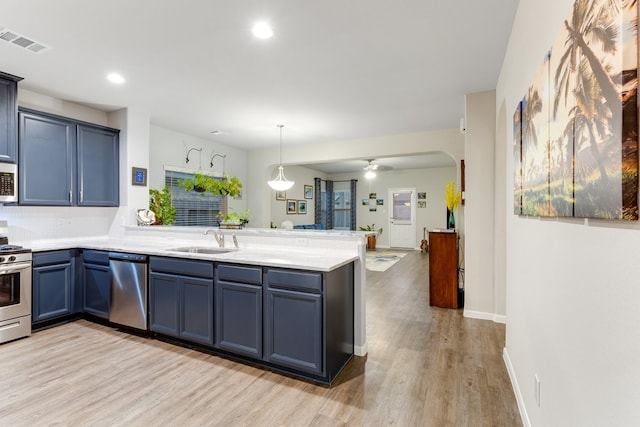 kitchen with visible vents, a peninsula, arched walkways, a sink, and appliances with stainless steel finishes