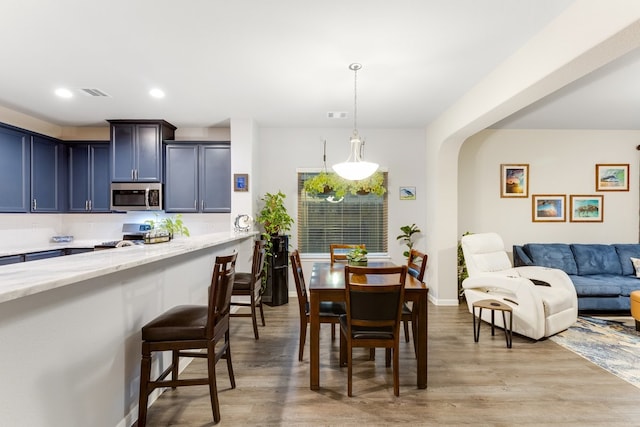 dining space featuring visible vents, light wood-style flooring, recessed lighting, arched walkways, and baseboards