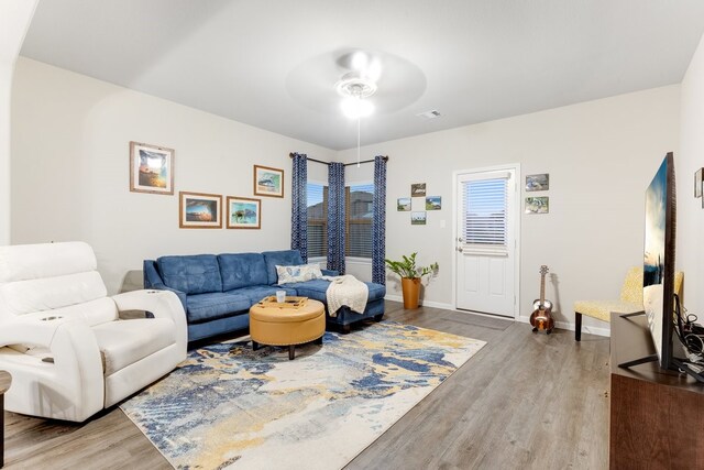 living area featuring baseboards, wood finished floors, visible vents, and ceiling fan