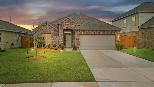 view of front facade with brick siding, a front lawn, roof with shingles, driveway, and an attached garage