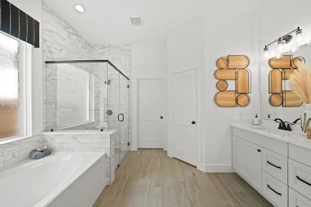 full bathroom featuring wood finished floors, vanity, visible vents, a bath, and a stall shower