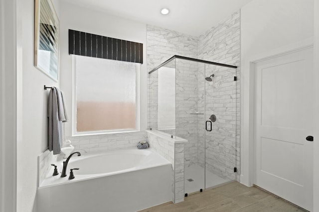 full bathroom featuring a stall shower, a garden tub, and wood finished floors