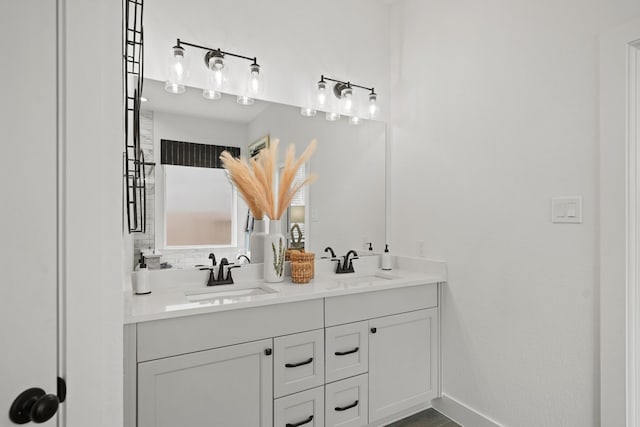 full bathroom featuring a sink, backsplash, baseboards, and double vanity