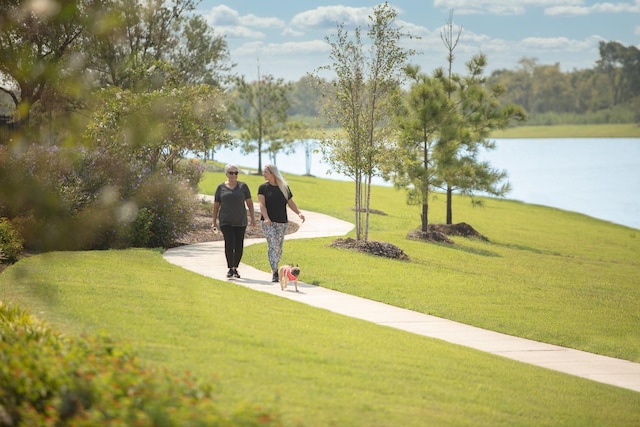 view of home's community with a water view and a yard