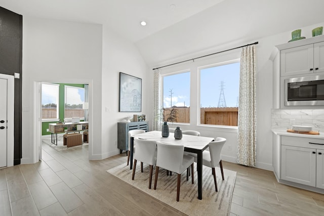 dining space featuring light wood-style floors, baseboards, vaulted ceiling, and recessed lighting