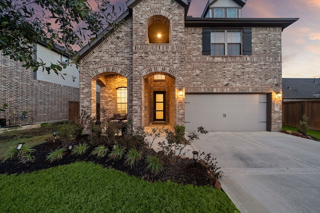 view of front of home featuring brick siding, an attached garage, driveway, and fence