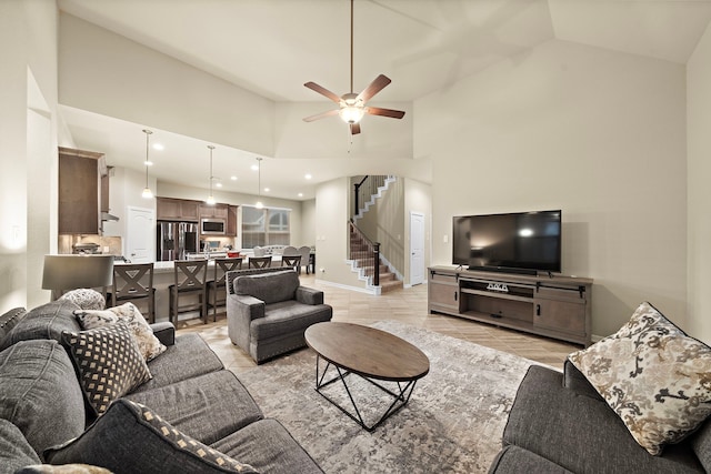 living room featuring light tile patterned floors, baseboards, high vaulted ceiling, ceiling fan, and stairs