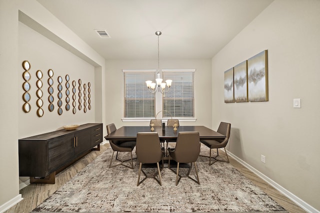 dining area featuring visible vents, baseboards, light wood-type flooring, and a chandelier