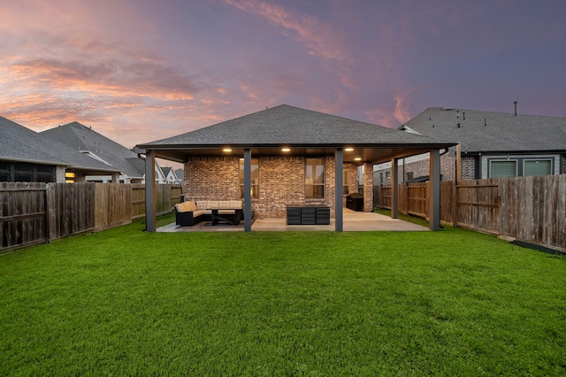 back of house with a lawn, a fenced backyard, a shingled roof, brick siding, and a patio area