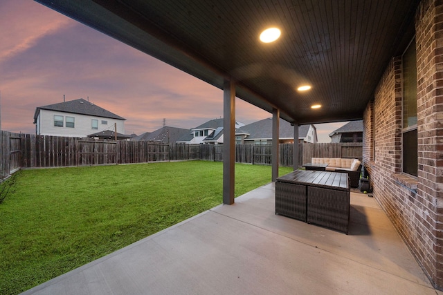 patio terrace at dusk featuring a lawn, a fenced backyard, and an outdoor hangout area