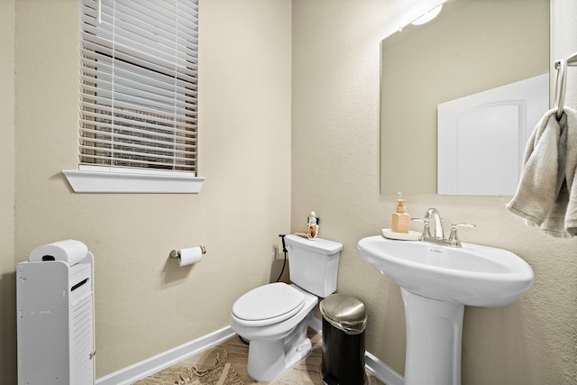 bathroom with toilet, baseboards, and a sink