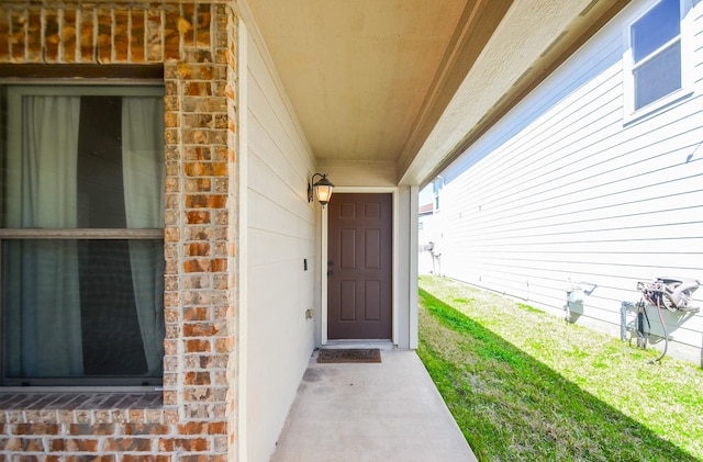 view of exterior entry with a garage and brick siding