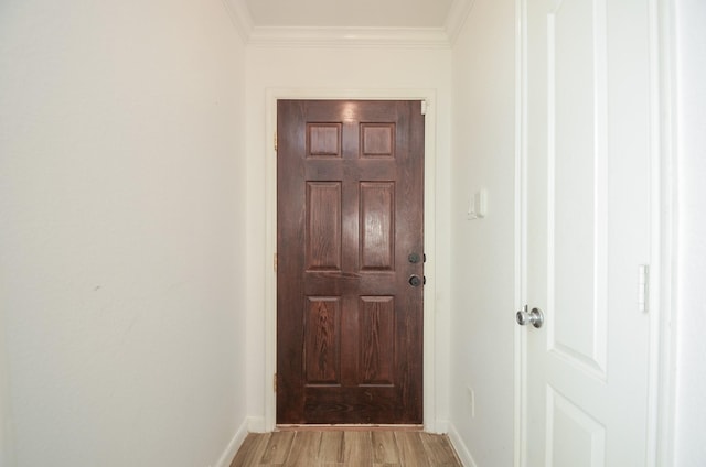 entryway with ornamental molding, light wood-style flooring, and baseboards