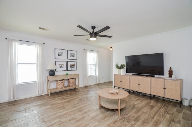 living area featuring a ceiling fan, visible vents, crown molding, and wood finished floors