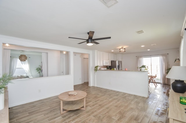 kitchen with light wood-type flooring, white microwave, stainless steel fridge, and visible vents