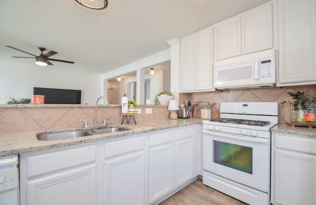 kitchen featuring white appliances, a sink, white cabinets, and tasteful backsplash