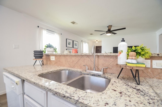 kitchen featuring visible vents, white cabinets, dishwasher, light stone countertops, and a sink