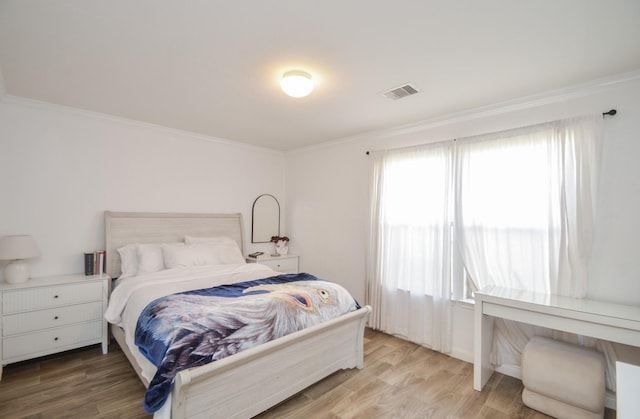 bedroom featuring wood finished floors, visible vents, and crown molding