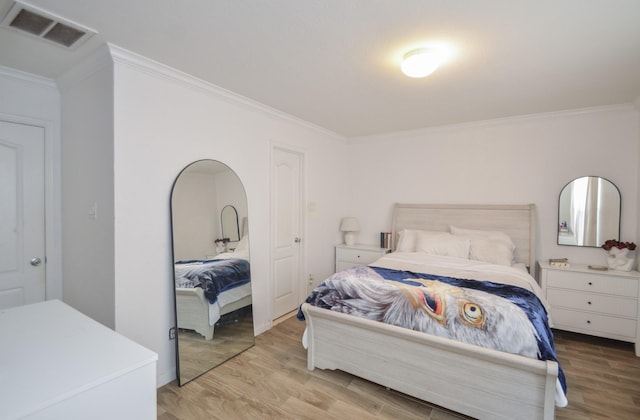 bedroom featuring visible vents, crown molding, and wood finished floors