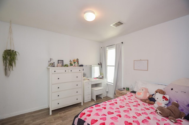 bedroom featuring baseboards, visible vents, and wood finished floors