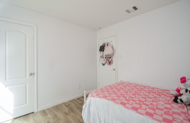 bedroom featuring visible vents, light wood-style flooring, and baseboards