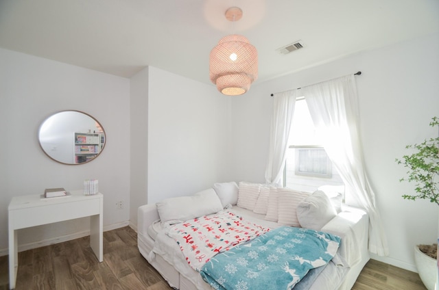 bedroom with wood finished floors, visible vents, and baseboards