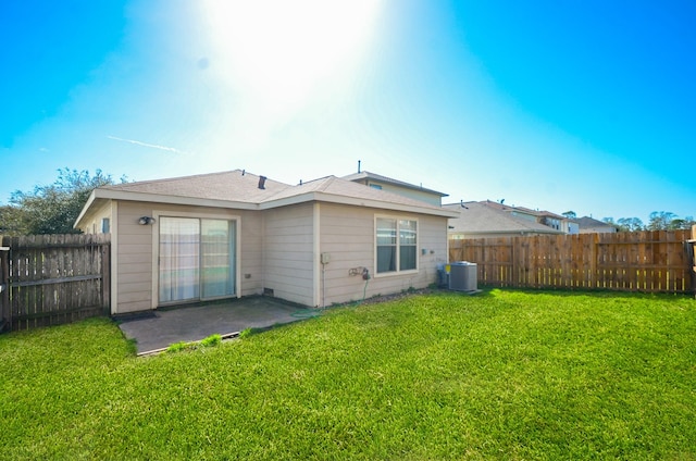 rear view of property featuring a patio, central AC unit, a lawn, and a fenced backyard